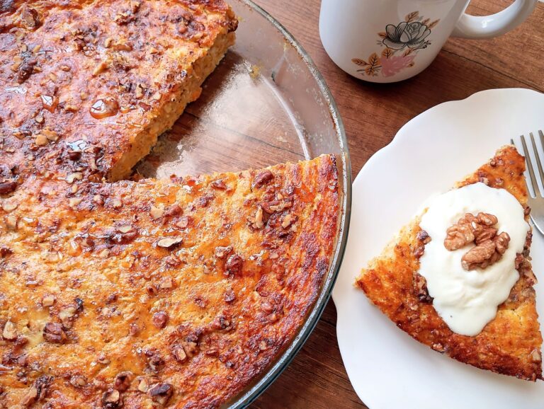 Cottage cheese breakfast bake with pumpkin in a baking dish with a slice served on a plate topped with cream and a walnut