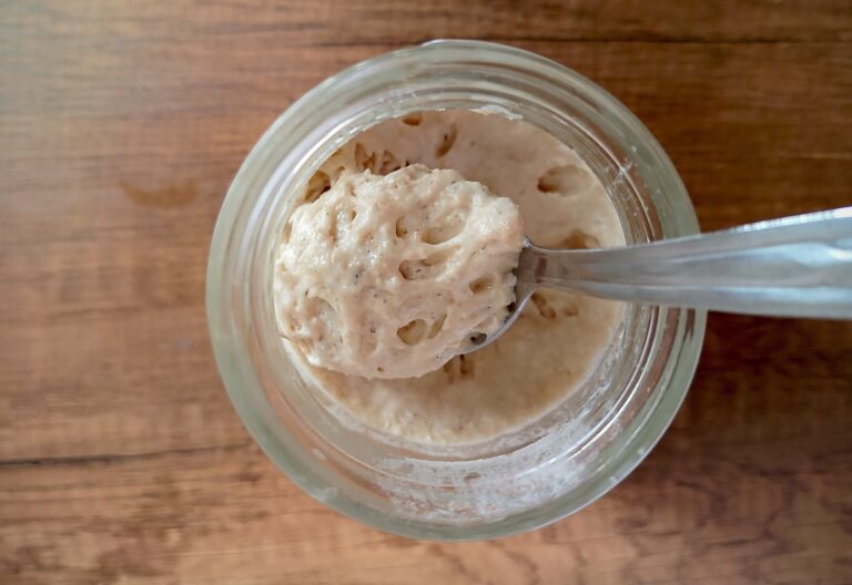 Spoon lifting some active sourdough starter out of jar