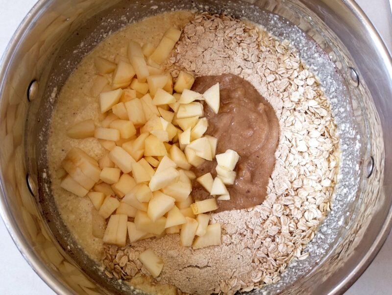 Adding oatmeal, chopped apples, and applesauce to wet ingredients for breakfast bake