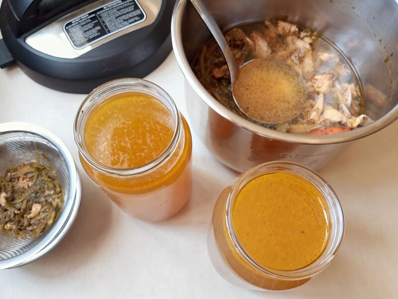 Pouring homemade bone broth from instant pot into jars