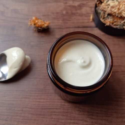 Calendula tallow cream in amber jar on wooden table