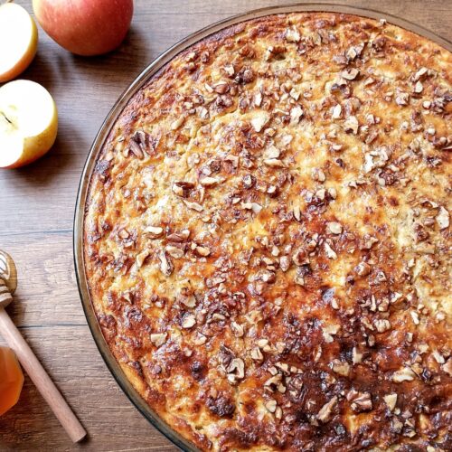 High protein breakfast bake with applesauce and apples in baking dish with honey dipper and apples on the side