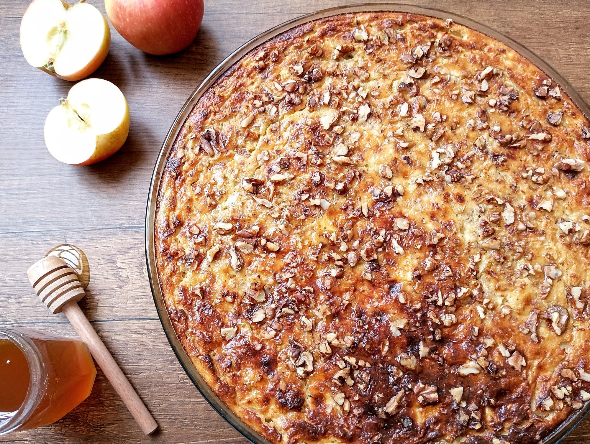 High protein breakfast bake with applesauce and apples in baking dish with honey dipper and apples on the side