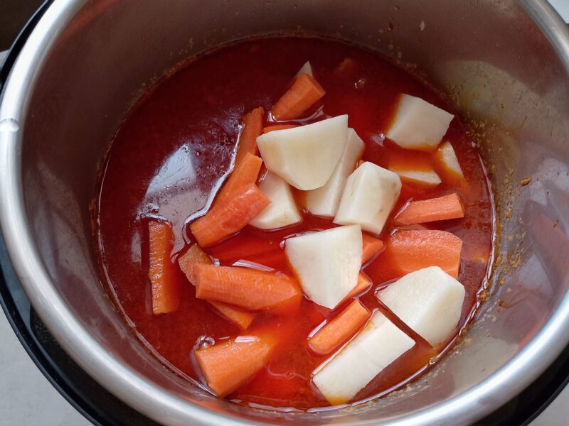Adding chopped potatoes and carrots to gizzard tagine