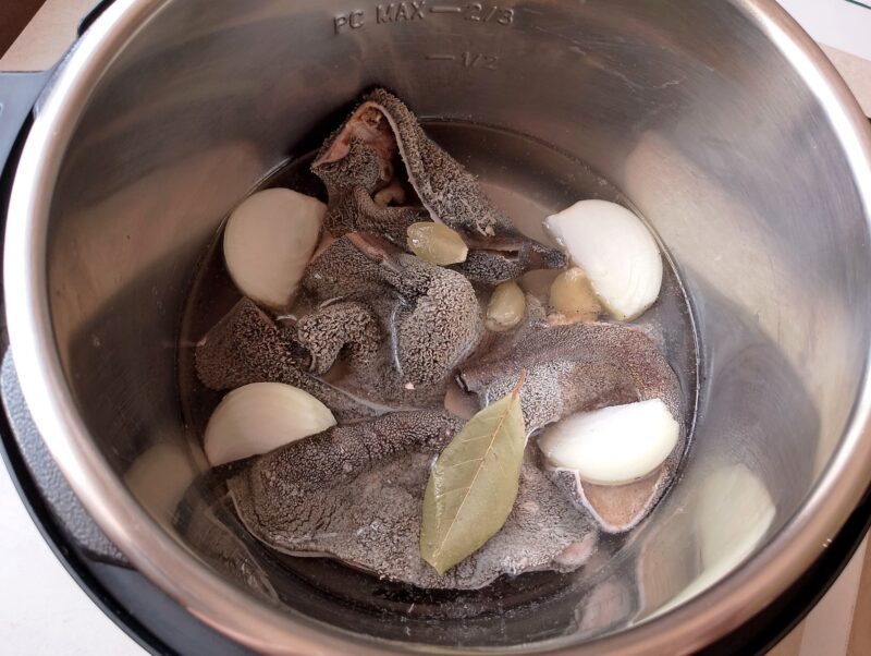 Tripe in instant pot with quartered onion, garlic, bay leaf, water,and salt