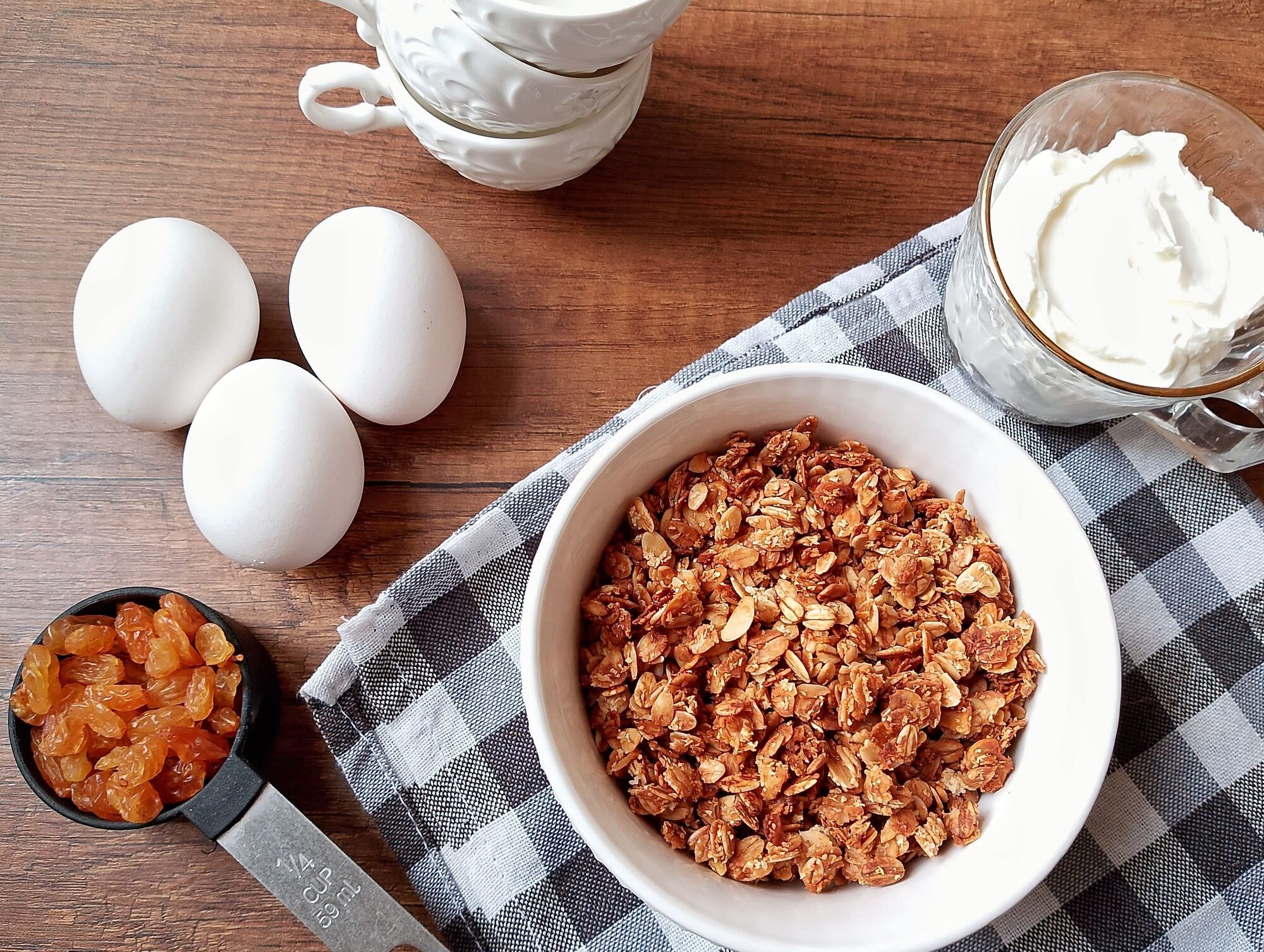 Homemaking habits: eggs, yogurt, granola, and raisins collected on wooden table