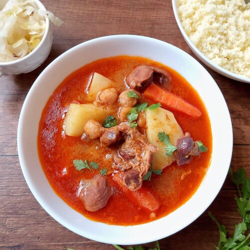 Instant pot gizzard tagine in bowl, garnished with cilantro, with a bowl of couscous on the side