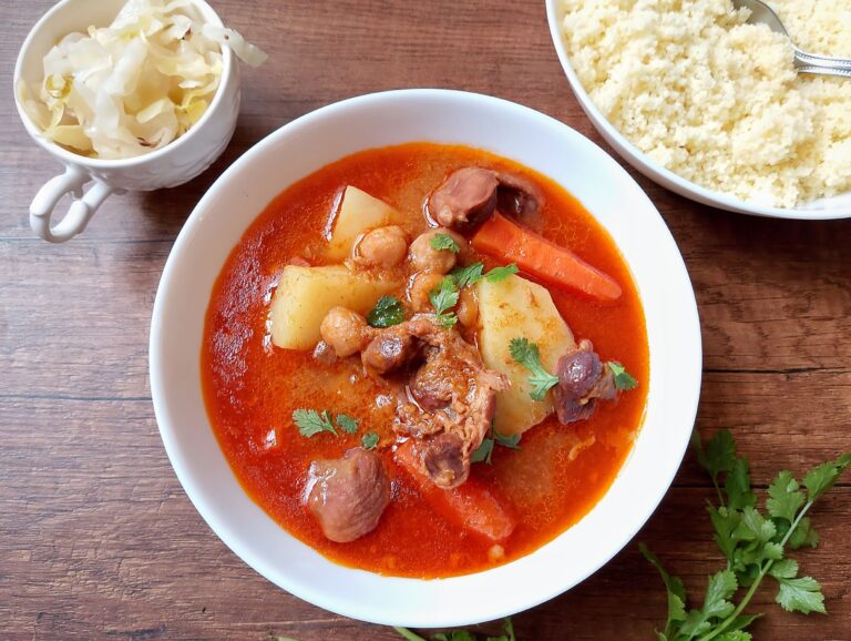 Instant pot gizzard tagine in bowl, garnished with cilantro, with a bowl of couscous on the side