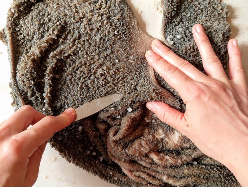 Scrubbing raw blanket tripe with salt and blunt side of a knife