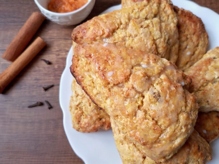 Sourdough pumpkin scones on white serving plate with cinnamon and bowl of pumpkin puree on the side