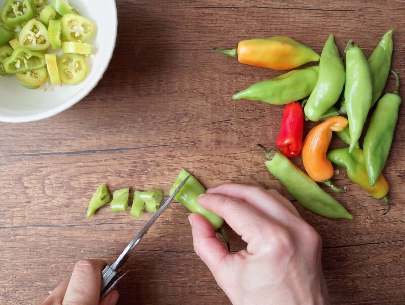 Womans hands slicing chili peppers