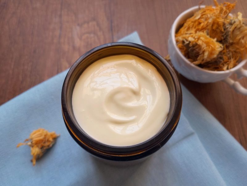 Transferring calendula body butter to amber jar for storage