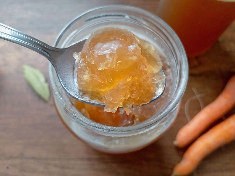Spoon lifting some gelled lamb broth out of jar