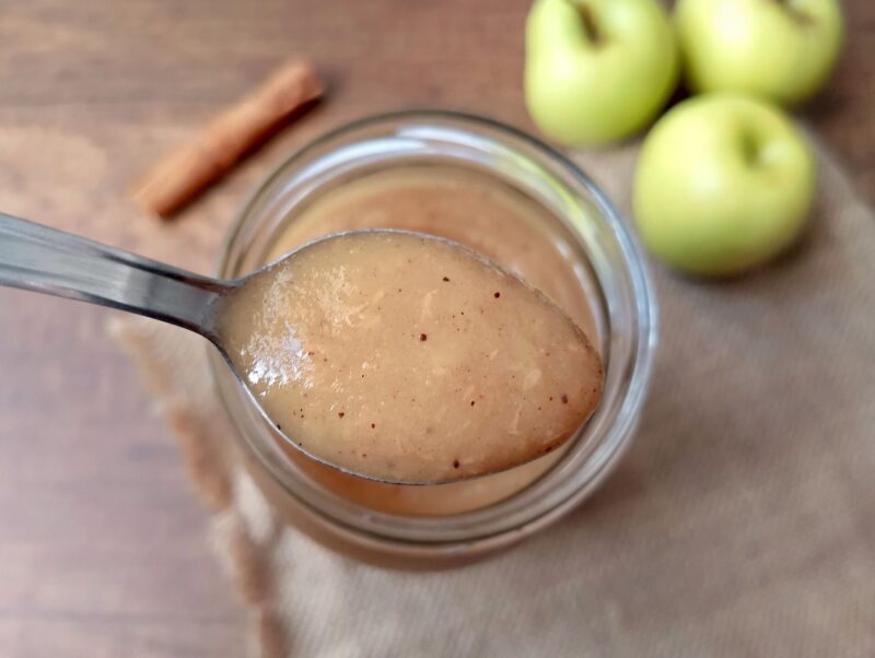 Spoon lifting some applesauce out of jar