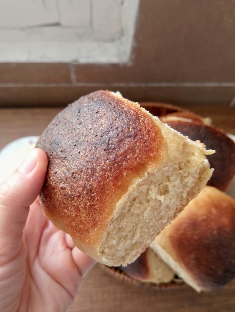Hand holding soft sourdough roll with whole wheat flour
