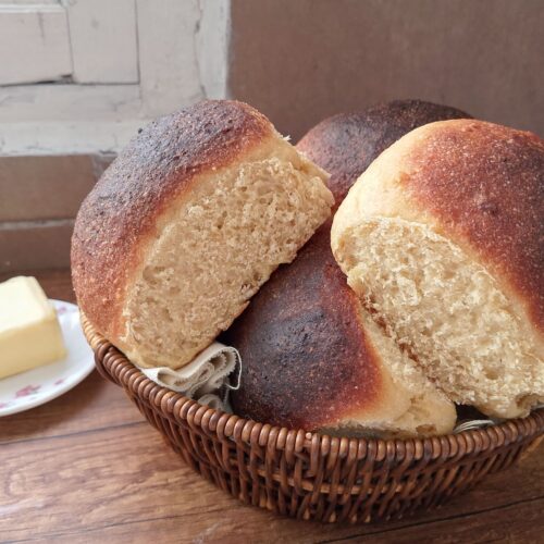 Soft sourdough rolls with whole wheat flour in basket on table with a butter dish on the side