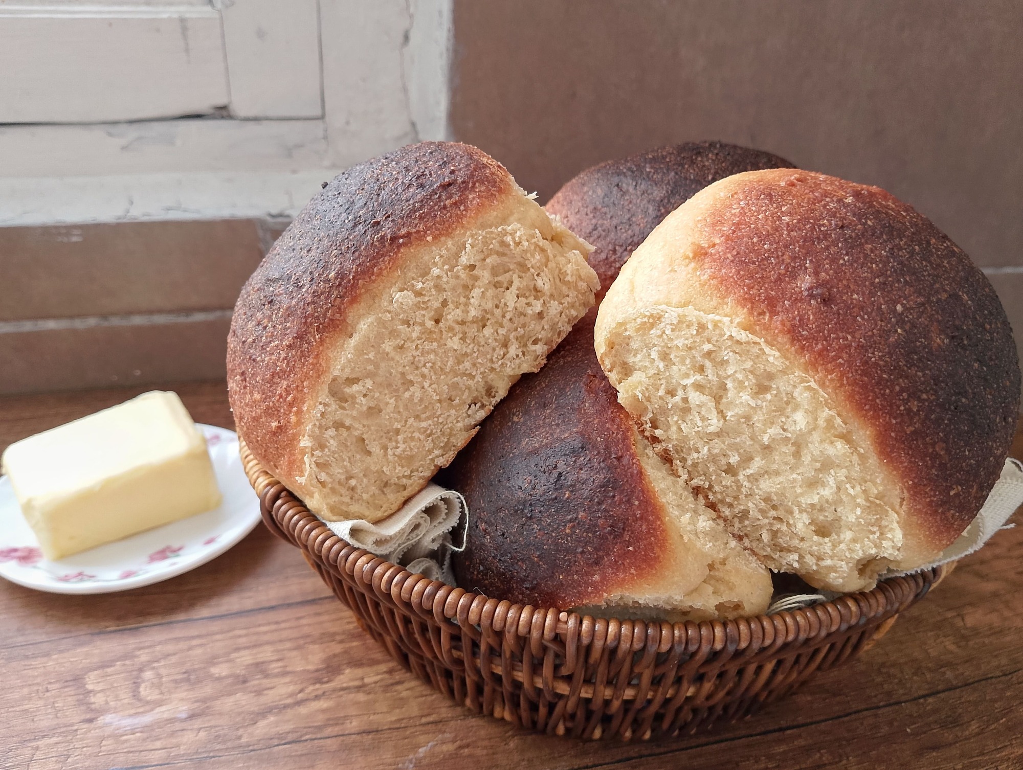 Soft sourdough rolls with whole wheat flour in basket on table with a butter dish on the side
