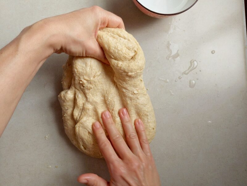 Womans hands stretching the dough during stretches and folds