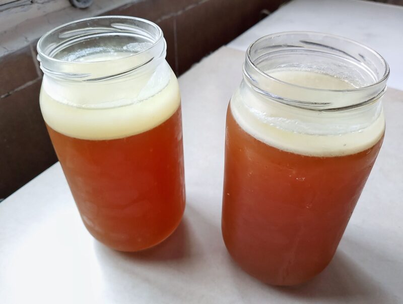 Jars of lamb bone broth with layer of solidified fat on top on table