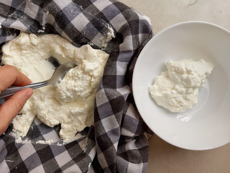 Transferring finished yogurt cheese from tea towel into a bowl