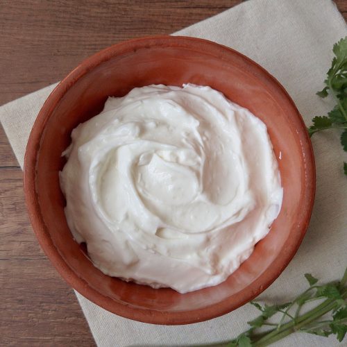 Yogurt cheese in terracotta bowl on wooden table